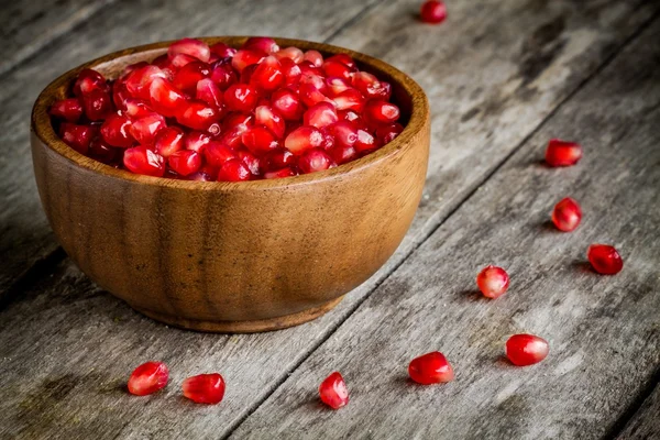 Ruby granatäpple korn i en träskål på ett bord — Stockfoto