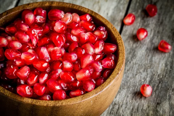 Ruby granatäpple korn närbild i en träskål på ett bord — Stockfoto