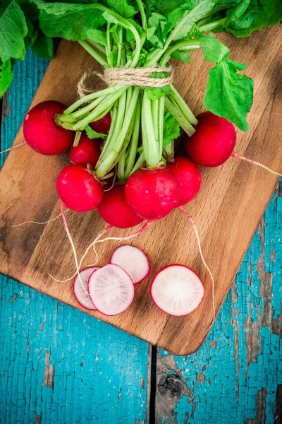 Rabanetes orgânicos frescos brilhantes com fatias e cebolas verdes na tábua de corte — Fotografia de Stock