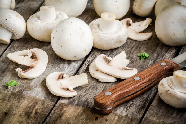 Raw sliced champignons on a rustic wooden table close up — Stock Photo, Image