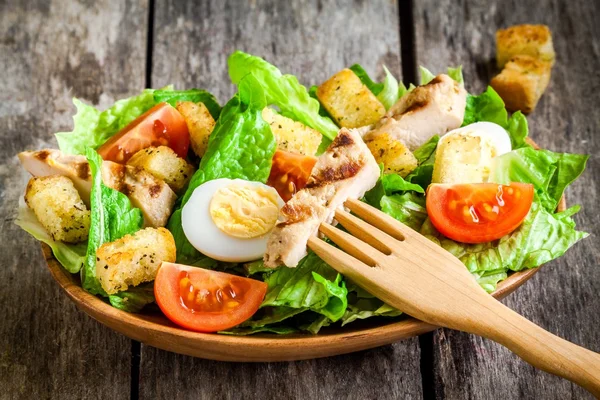 Salada Caesar com croutons, ovos de codorna, tomate cereja e frango grelhado em placa de madeira — Fotografia de Stock