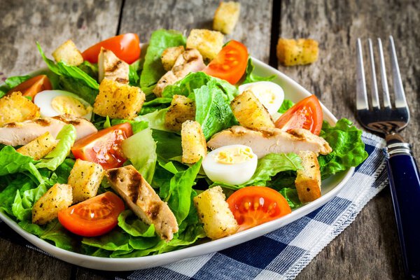 Caesar salad with croutons, quail eggs, cherry tomatoes and grilled chicken