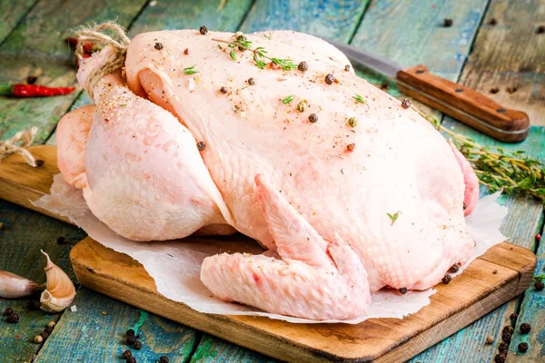 Frango cru orgânico com tomilho e pimentas em uma mesa rústica — Fotografia de Stock