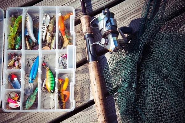Señuelos de pesca en cajas de aparejos con varilla giratoria y red Imagen de stock