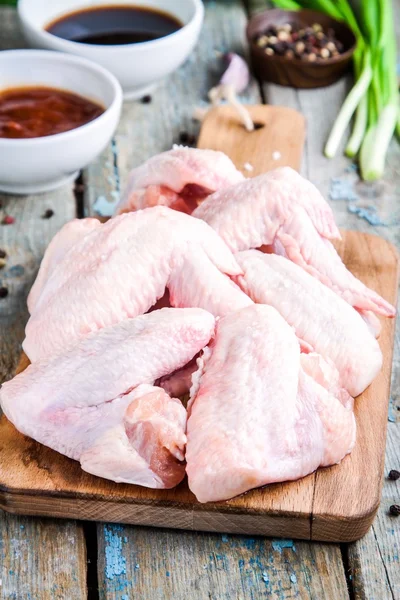 Alas frescas de pollo crudo con especias en un primer plano de la tabla de cortar —  Fotos de Stock