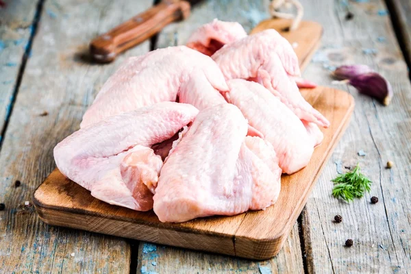Alas frescas de pollo crudo en una tabla de cortar —  Fotos de Stock