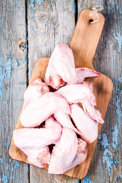 Alas frescas de pollo crudo en una tabla de cortar —  Fotos de Stock