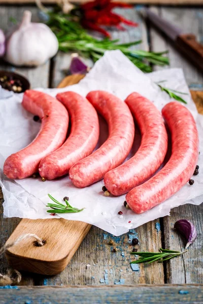 Rohe hausgemachte Würstchen auf Schneidebrett Stockfoto