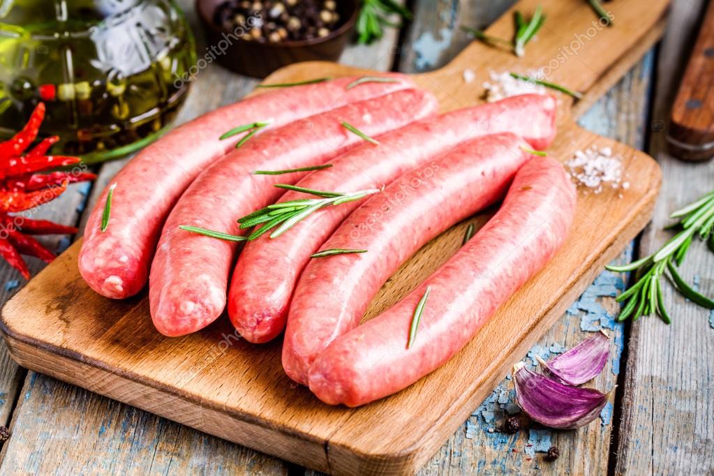 Raw homemade sausages on cutting board with rosemary — Stock Photo