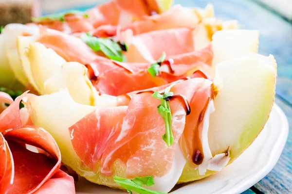 Salad of melon with thin slices of prosciutto, arugula leaves and balsamic sauce closeup — Stock Photo, Image