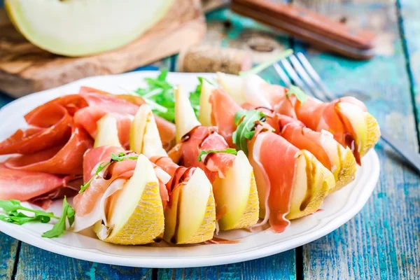 Salad of melon with thin slices of prosciutto, arugula leaves and balsamic sauce — Stock Photo, Image
