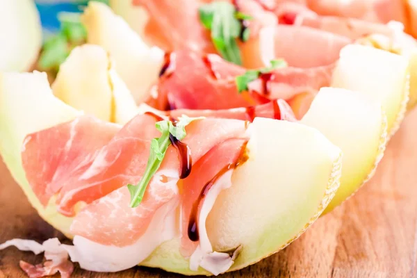 Melon with thin slices of prosciutto and arugula leaves — Stock Photo, Image