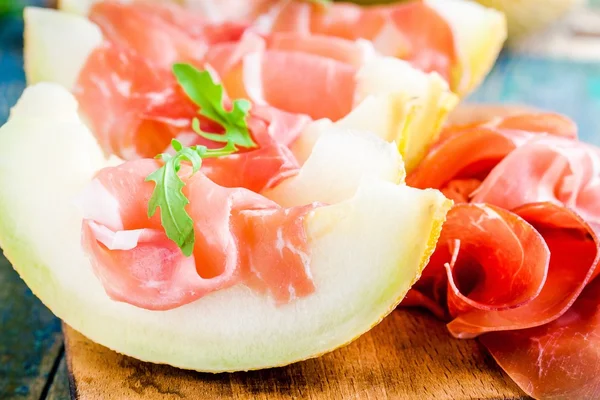 Melone mit dünnen Schinken-Scheiben und Rucolablättern — Stockfoto