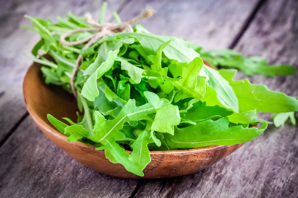 Pacote de arugula orgânica em uma tigela de madeira — Fotografia de Stock