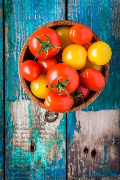 Tomates cereja amarelos e vermelhos em uma tigela na mesa de madeira rústica — Fotografia de Stock