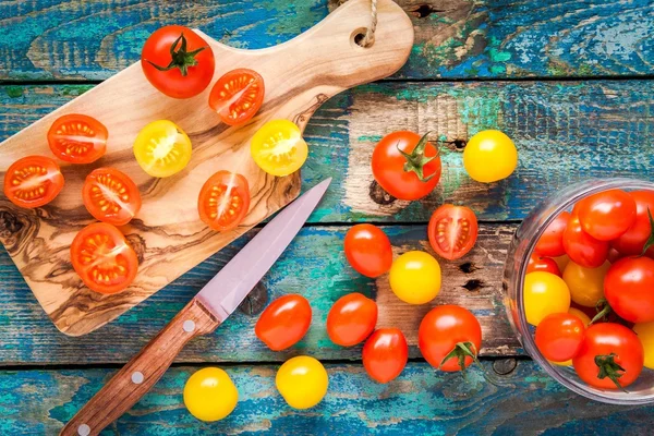 Tomates cereja amarelos e vermelhos cortados em uma tábua de corte — Fotografia de Stock