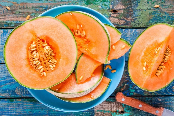 Melon mûr tranché sur une assiette sur un fond rustique — Photo