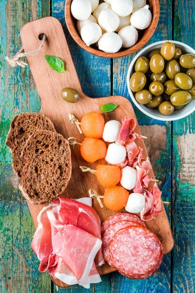 モッツァレラチーズ、生ハム、サラミ、オリーブのパンとメロンのカナッペ — ストック写真