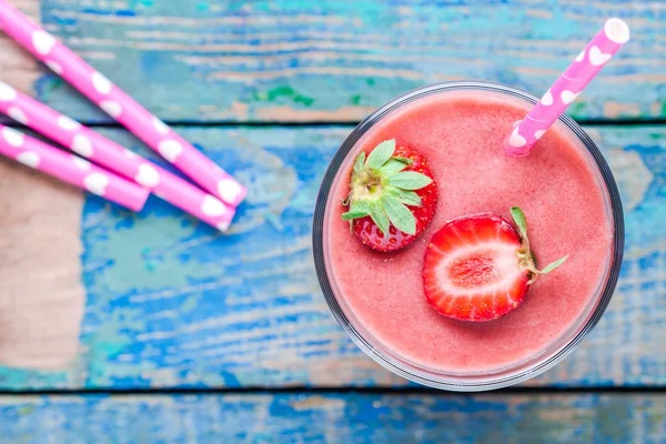 strawberry smoothie in a glass with a straw top view