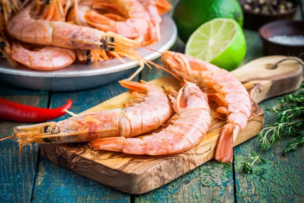 Fresh raw prawns on a wooden cutting board with salt, pepper, lime — Stock Photo, Image