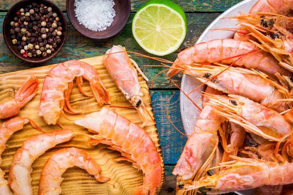 Fresh shrimps on wooden board with salt, pepper, lime closeup — Stock Photo, Image