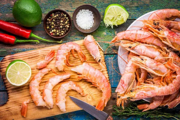 Fresh shrimps on wooden board with salt, chili pepper, lime — Stockfoto