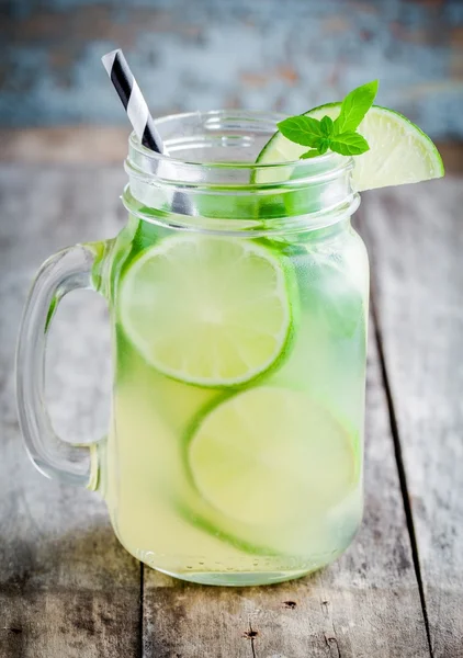 Limonada casera con lima, menta en un frasco de albañil sobre una mesa de madera —  Fotos de Stock