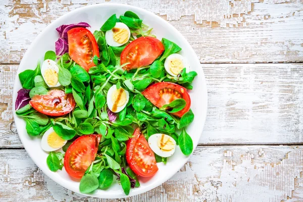 Fresh green salad with lamb's lettuce, tomatoes and quail eggs — Stock Photo, Image