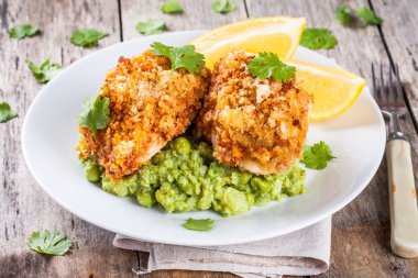 Baked cod fish in breadcrumbs with mashed green peas and broccoli clipart
