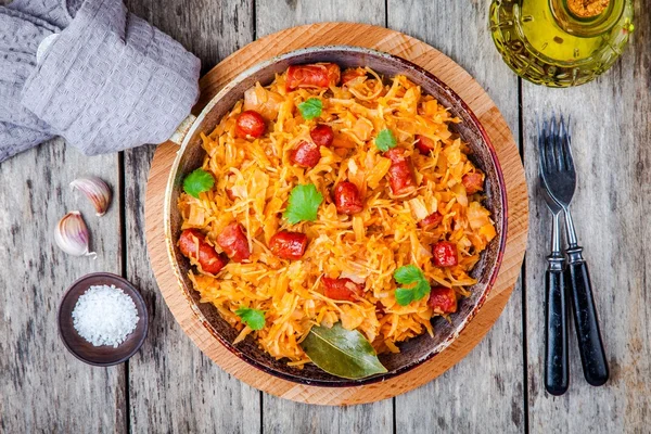 Homemade braised sauerkraut with smoked sausages in a frying pan — Stock Photo, Image