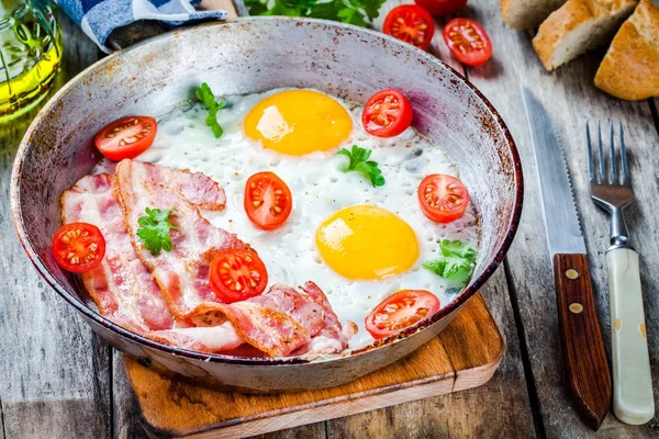 Breakfast with fried eggs, bacon, tomatoes and parsley — Stock Image Breakfast with fried eggs, bacon, tomatoes and parsley Stock Image