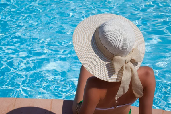 Mujer joven sentada en la repisa de la piscina — Foto de Stock