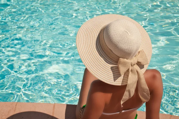 Jeune femme assise sur le rebord de la piscine — Photo