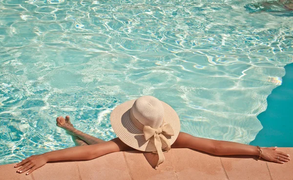 Mujer en un sombrero de piscina relajante en una piscina azul — Foto de Stock