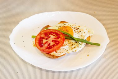 Kızarmış yumurtalı domatesli, biberli ve yeşil soğanlı bir tabakta.