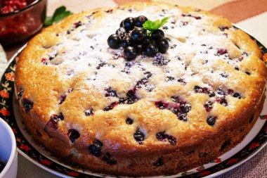 Pie with black currant berries sprinkled with powdered sugar close-up. Delicious pastries.