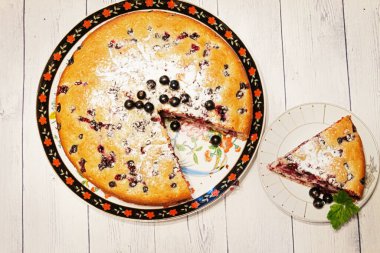 Pie with black currant berries sprinkled with powdered sugar close-up. Delicious pastries.