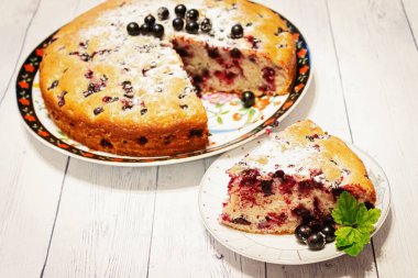 Pie with black currant berries sprinkled with powdered sugar close-up. Delicious pastries.