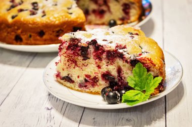 Pie with black currant berries sprinkled with powdered sugar close-up. Delicious pastries.