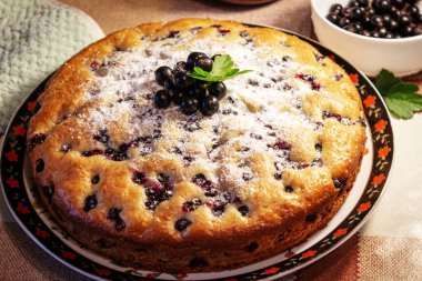 Pie with black currant berries sprinkled with powdered sugar close-up. Delicious pastries.
