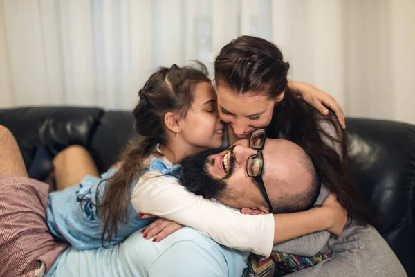 Babam kanepede aileye katılır ve herkesi gıdıklamaya başlar. Genç kaygısız ebeveynler ve küçük kız gülüyor. Evde sarılıp oynuyorlar. Kanepede eğlenceli bir oyun oynuyorlar..