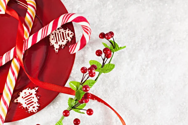 Bastoncini di zucchero su piatto rosso con decorazione natalizia intorno — Foto Stock