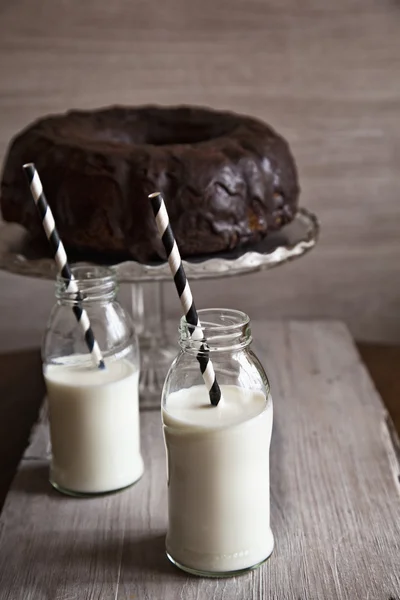 Bolo de pacote e duas garrafas de leite com palhas — Fotografia de Stock