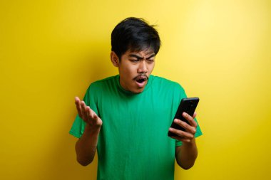 Çekici Asyalı genç adam telefonunda mesajlaşırken okuyor. Kötü haber, sarı arka planda ağlayan üzgün surat.