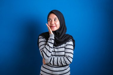 Portrait of Asian muslim student college girl smiling and thinking gesture, finding solution on problems