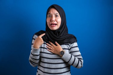 Asyalı kadın kendini mutsuz bir ifadeyle gösteriyor. Sanki suçlandığı için kafası karışmış ve kime sormuş gibi. Ben.?