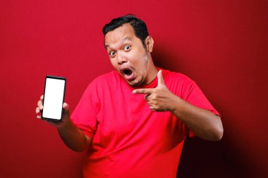 Asyalı erkekler akıllı telefon kullanıyor. Telefona bakıyor ve çok şaşırmış görünüyor. Kırmızı arka planda eski kırmızı bir gömlek giyiyor..