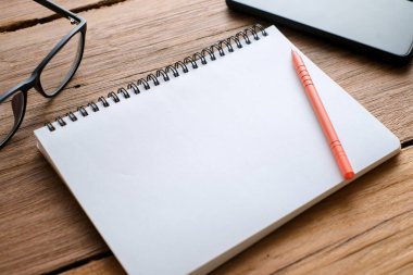 Tahta masa, defter, gözlük, kalem, dekoratif bitkiler. Tahta tablo ve kopya alanı olan kırtasiye malzemesinin üst görünümü, düz konum.