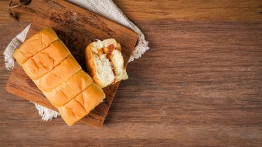 Tahta bir masada içi et ipi ve mayonez dolu kesilmiş ekmek.