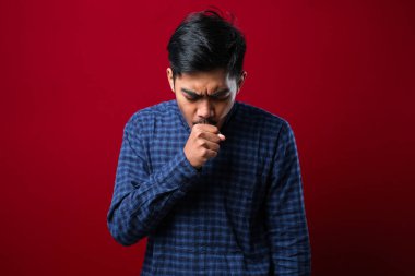 Boğazı ağrıyan Asyalı genç adam kırmızı arka planda alerjisi olan adam konsepti.